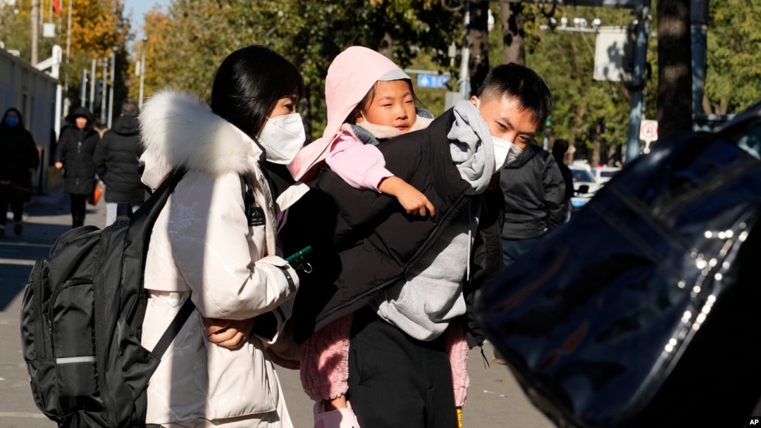 一名男子背著女孩離開北京的一所兒童醫院。(2023年11月24日)