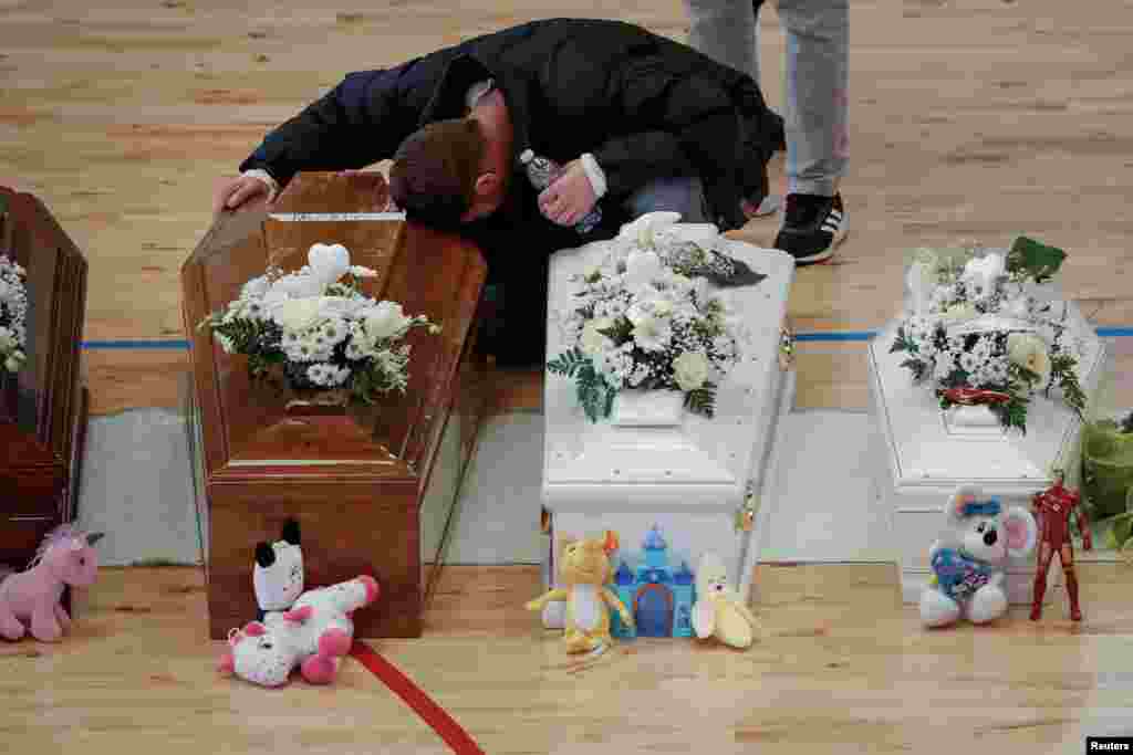 A mourner mourns near coffins during a lying-in-state for victims who died in a migrant shipwreck, in Crotone, Italy, March 1, 2023.