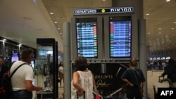 FILE - Passengers look at a departure board at Ben Gurion Airport near Tel Aviv, Israel, on Oct. 7, 2023. On Oct. 16, the Australian government said three evacuation flights had left Tel Aviv for Dubai. 