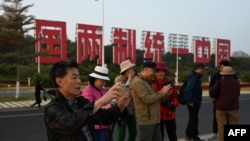 资料照:中国福建厦门竖立起一个台湾金门岛可以看到的“一国两制统一中国”的大型标语牌,旅游者在前拍照。(2024年1月12日)