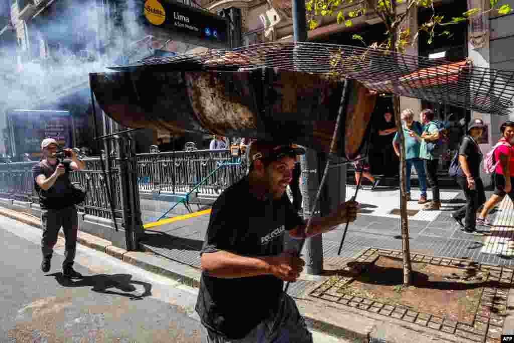 A man carrying a griller on his head takes part in a demonstration near the Argentine Congress during a national strike against the government of Javier Milei in Buenos Aires. President Javier Milei faces the first national strike in just 45 days of government against his draconian fiscal adjustment and his plan to reform more than a thousand laws and regulations that governed for decades. 
