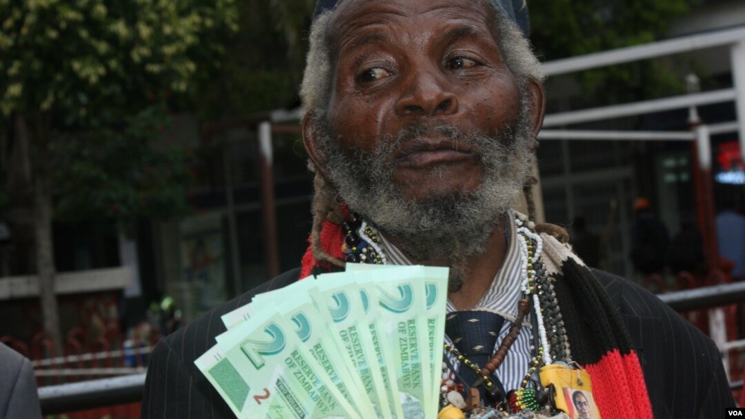 Holding bills of new Zimbabwean money, a man welcomes the introduction of 'bond notes' saying the move will ease cash shortages in the country, in Harare, Zimbabwe, Nov. 28, 2016. (S. Mhofu/VOA)