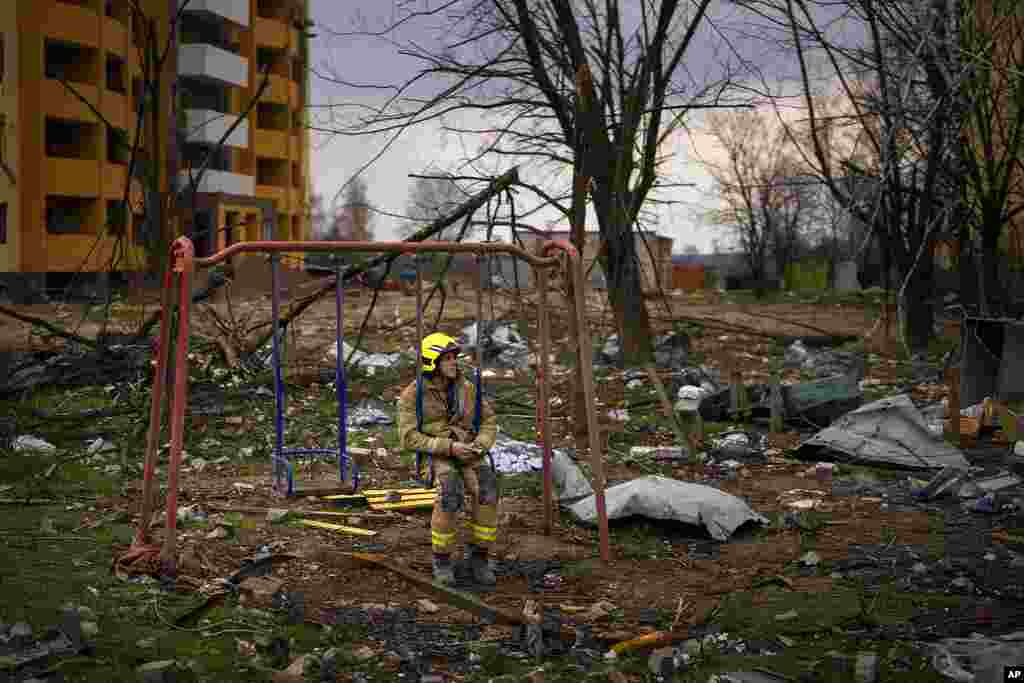A firefighter sits on a swing next to a building destroyed by a Russian bomb in Chernihiv, Ukraine.