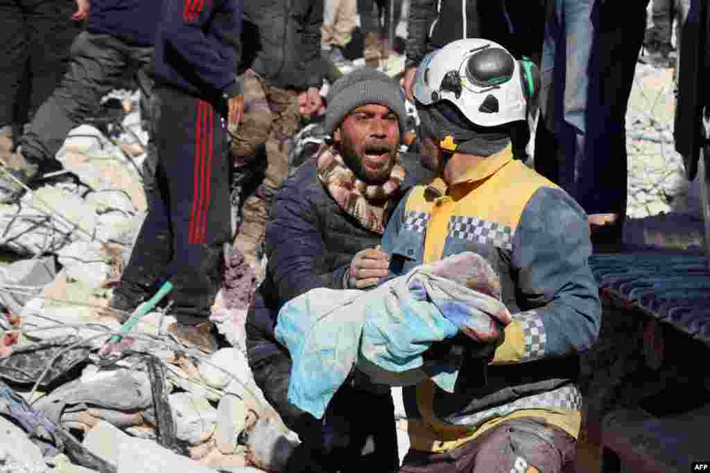 A man reacts as the body of his baby pulled out from the rubble, is taken away by a Syrian White Helmet rescue worker, in the town of Harim in Syria's rebel-held northwestern Idlib province, Feb. 8, 2023.