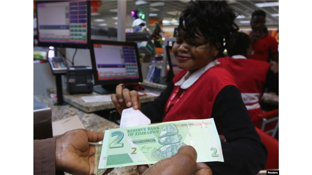 A till operator poses with new bond notes at a supermarket in Harare, Nov. 28, 2016.