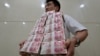中国山西太原一家银行职员手捧成捆的人民币百元现钞。（资料照片）