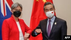 资料照：在印尼度假胜地巴厘岛努沙杜瓦举行的二十国集团外长会议期间，澳大利亚外交部长黄英贤(左)与中国外交部长王毅碰肘互致问候。（2022年7月8日）