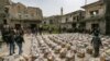 FILE - Locals arrive to receive humanitarian food aid packages being handed over by a volunteer team of first responders in the town of al-Najieh in the western countryside of Syria's rebel-held northwestern Idlib province on April 6, 2022.