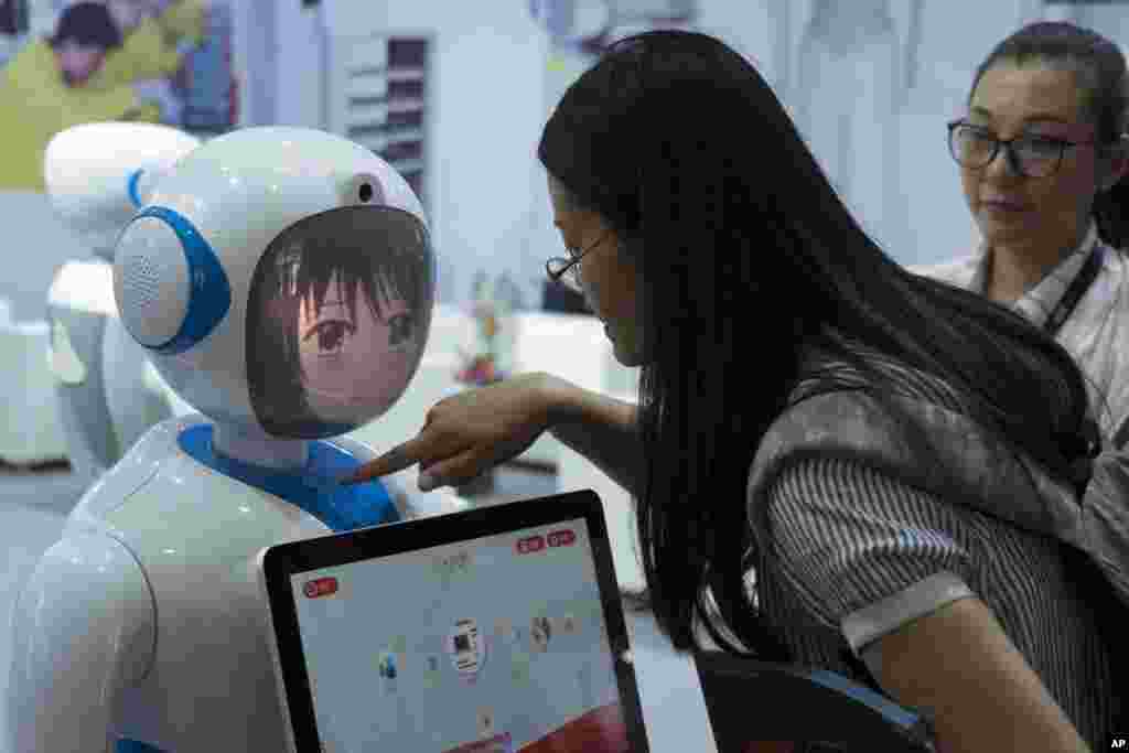 2018年6月15日在中国上海举行的2018亚洲消费电子展上,中国穿山甲机器人公司设计的机器人和参观者互动。中国大力研发机器人。