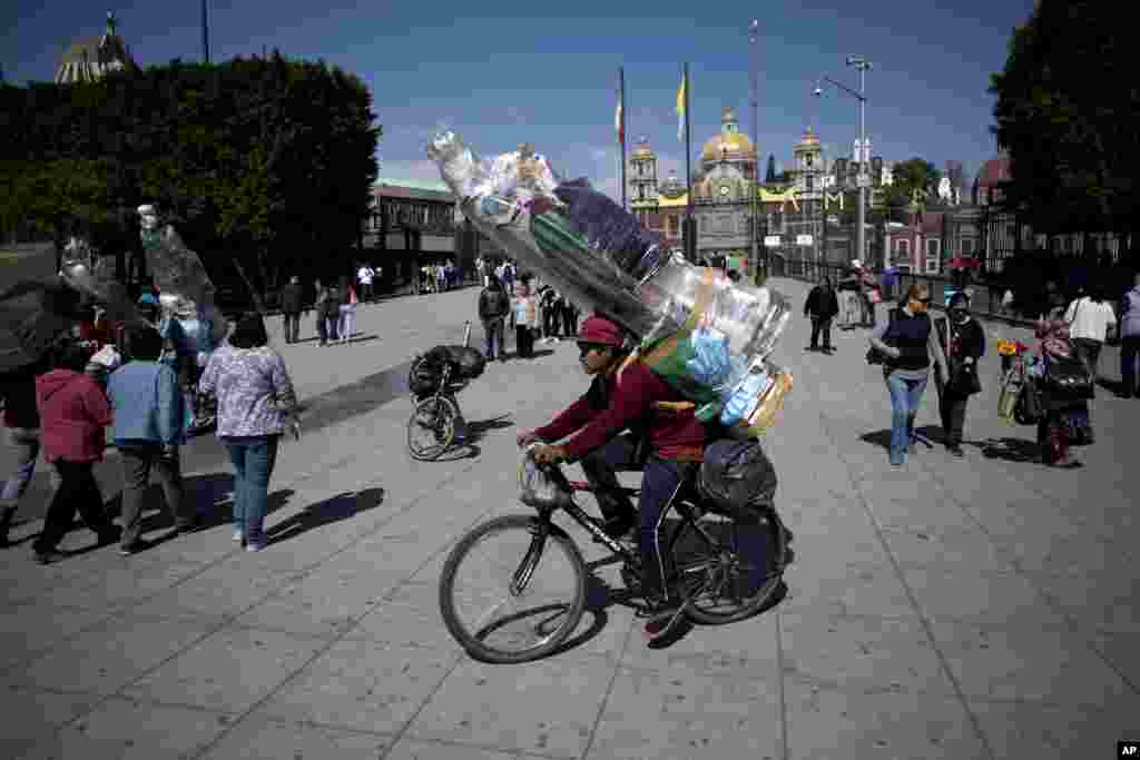A cyclist carries two large statues of the Virgin Mary in Mexico City, Nov. 22, 2017.