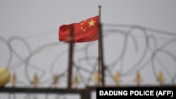 中国新疆地区喀什南部的一个住宅区外，铁丝网后面能看到高挂的中国国旗。（2019年6月4日）
