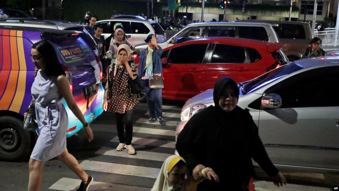 FILE - People cross a road during a rush hour traffic in Jakarta, Indonesia, March 29, 2019. Indonesia's air quality has deteriorated from among the cleanest in the world to one of the most polluted over the past two decades.