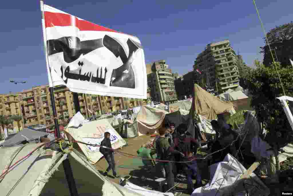 2012年12月10日,反穆尔西的抗议者坐在埃及解放广场帐篷外,头顶旗帜上的口号是:“不要这部宪法!”