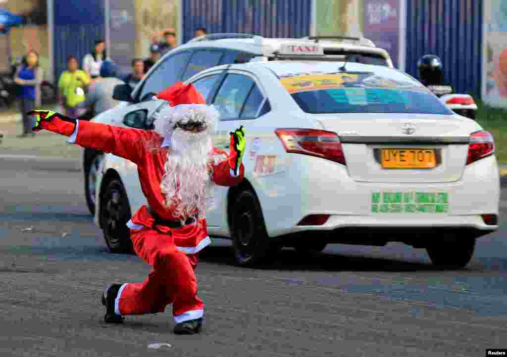 Traffic enforcer Ramiro Hinojas, 51, wears a Santa Claus costume while directing motorists through traffic at an intersection in Pasay City, Metro Manila, Philippines.