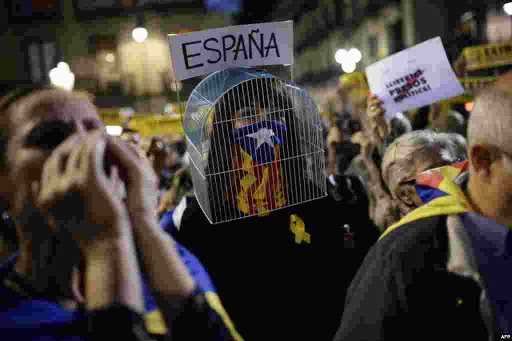A woman with a cage over her head and her face covered with a Catalan pro-independence Estelada flag takes part in a demonstration in Barcelona, to protest against the detention of Catalan officials in Madrid, Spain.