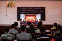 广西柳州一个村庄的村民正在观看在北京人大会堂举行的全国脱贫攻坚总结表彰大会的电视直播。（2021年2月25日）
