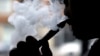 FILE - A smoker demonstrates an e-cigarette at Vape store in Chicago, April 23, 2014. A new study found that toxicity levels of e-cigarettes can fluctuate with the temperature, type and age of the device, a new study has found.