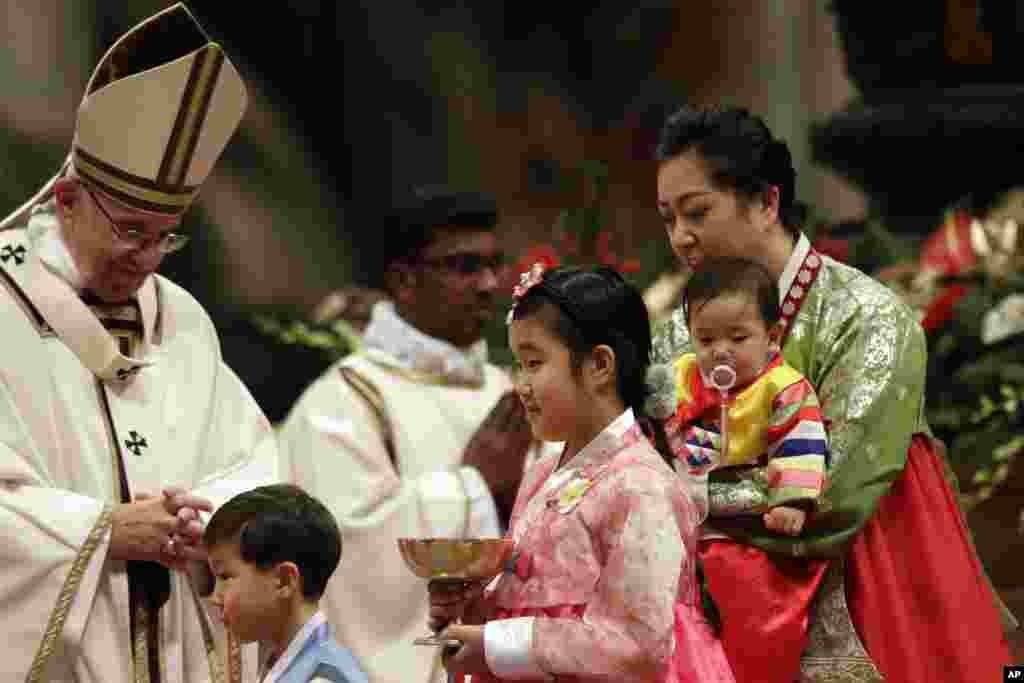 Faithful walk past Pope Francis during the Christmas Eve Mass celebrated in St. Peter's Basilica at the Vatican, Dec. 24, 2016.