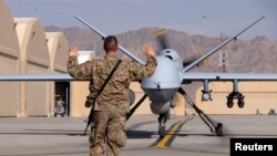 2016年3月9日，阿富汗坎大哈机场，一名美国空军士兵指挥一架无人机进入跑道。