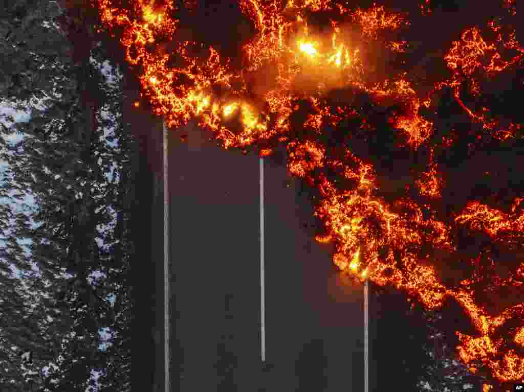 Molten lava flows on the road to the Blue Lagoon, Grindavik, after the volcanic eruption that started Wednesday, on the Reykjanes Peninsula in Iceland, Nov. 21, 2024. (AP Photo/Marco di Marco)