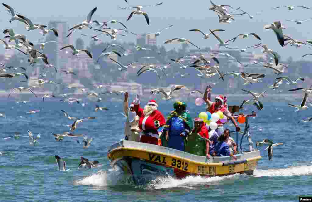 A man dressed in a Santa Claus outfit waves to people from a fisherman's boat on Christmas Eve along the coast of Valparaiso, Chile, Dec. 24, 2017.