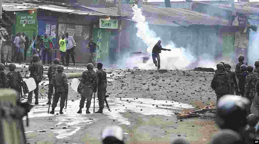 A supporter of opposition leader Raila Odinga throws a canister of tear gas towards riot police during running battles with police in Kibera Slums in Nairobi, Kenya.