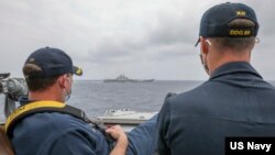 资料照片：美国海军公布的照片显示，两位美国海军中校罗伯特·J·布里格斯与理查德·D·斯莱2021年4月4日在阿利·伯克级导弹驱逐舰“马斯廷号”驾驶舱进行水面接触观察。照片中可见中国"辽宁号"航空母舰及其舷号。