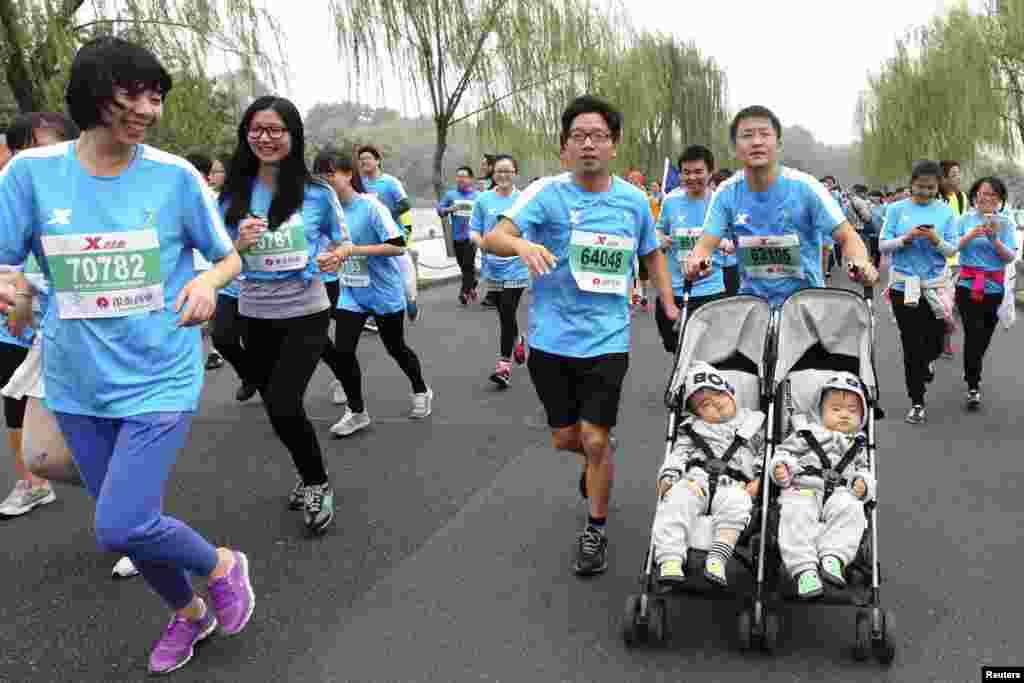 在中国浙江省杭州市举办国际马拉松赛时,一名男子推着婴儿车跑步,车上有13个月大的双胞胎婴儿(2014年11月2日)。