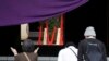 2015年4月21日，人们在一年一度的春季节日参拜位于东京的靖国神社，可以看到背景中心位置是首相安倍晋三供奉的祭品。安倍周二向供奉了已被判刑的二战首领的靖国神社送去宗教祭品，这可能是他不会在出访亚洲和美国前参拜这座有争议的神社的信号。