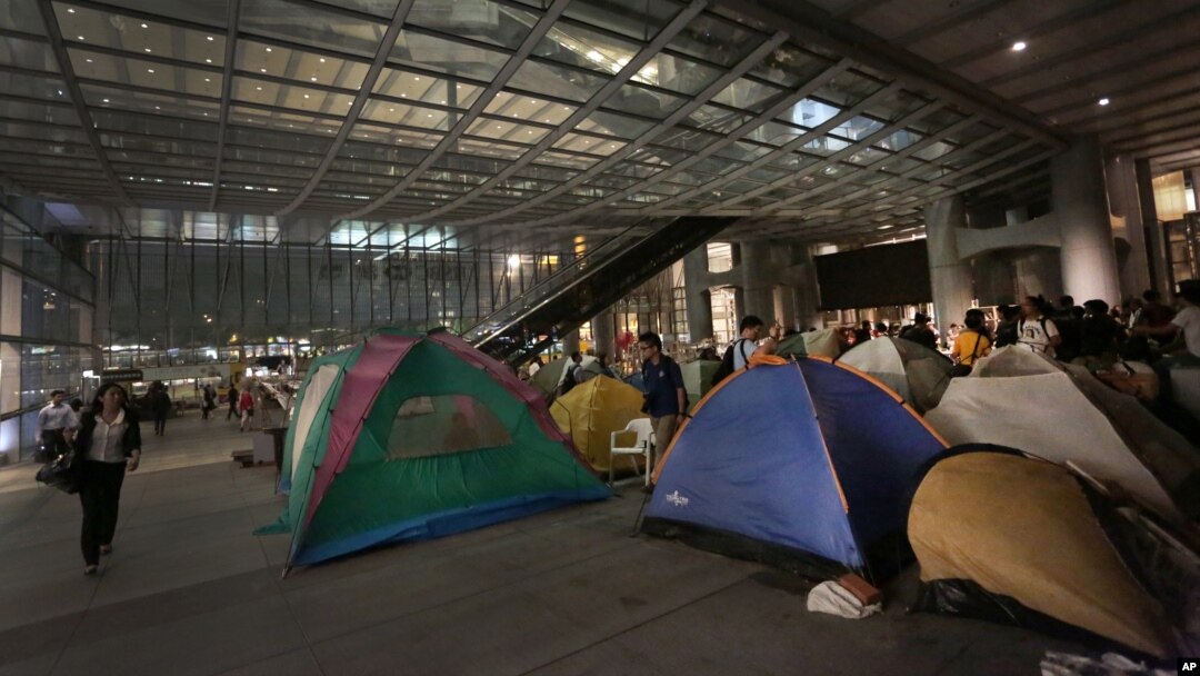 People walk past protesters' tents outside the HSBC headquarters in Hong Kong, August. 27, 2012.