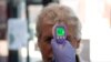 In this June 9, 2020 photo, a patient has his temperature taken with a non-contact infrared thermometer on arrival at Freshney Green Primary Care Center in Grimsby, northeast England.