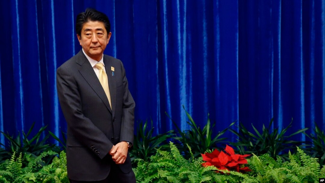 FILE - Japan's Prime Minister Shinzo Abe wait to meet China's President Xi Jinping, during their meeting at the Great Hall of the People, on the sidelines of the Asia Pacific Economic Cooperation (APEC) meetings, in Beijing, Nov. 10, 2014.