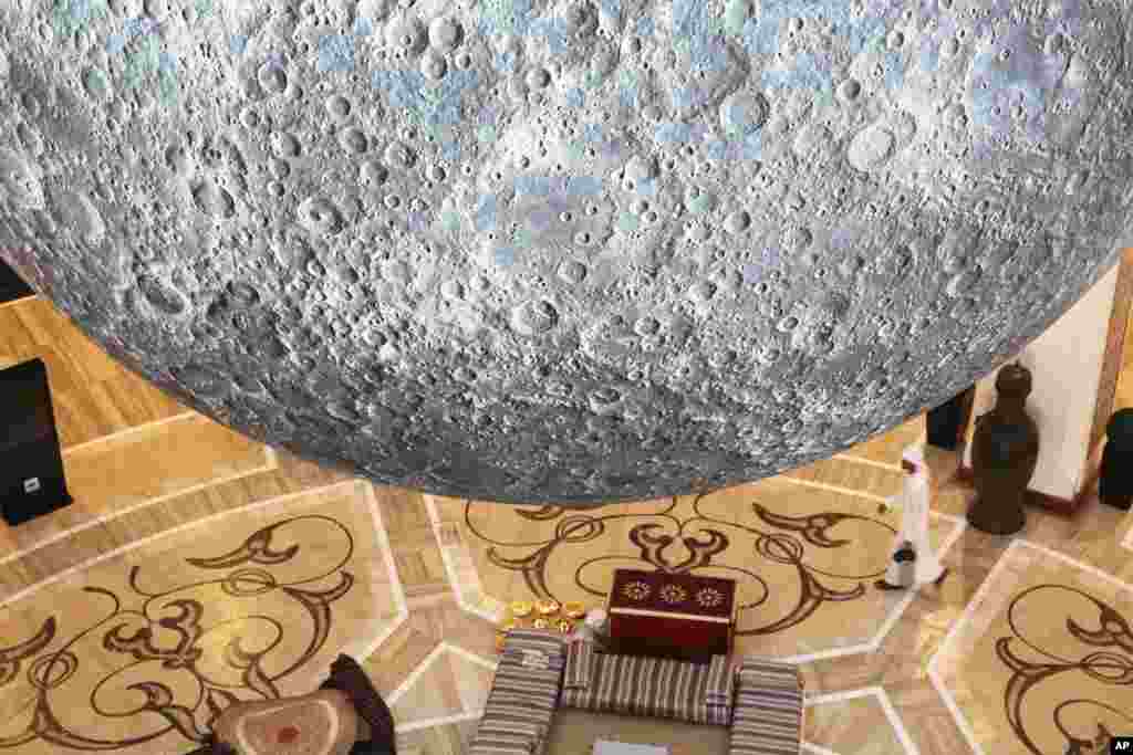 An Emirati in traditional robes walks underneath a giant model of the moon at the Dubai Mall in Dubai, United Arab Emirates. The model is called the "Museum of the Moon" and was designed by British artist Luke Jerram.