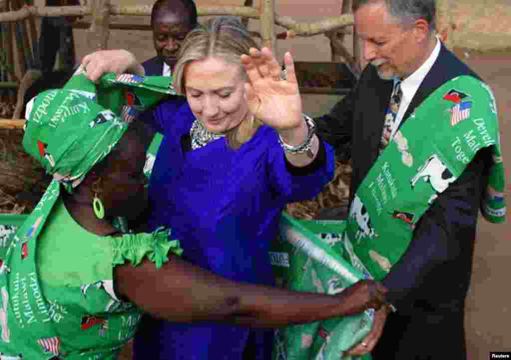 Clinton is dressed by Emmie Phiri, chairperson of the dairy farmers during her visit to Malawi, August 5, 2012.