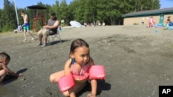 Milana Acuna, 5, makes a mud creation while at Goose Lake as her father, Manny Acuna, looks on, July 5, 2019, in Anchorage, Alaska.