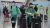身穿防护服和戴口罩的旅客抵达香港国际机场。（2020年3月23日）