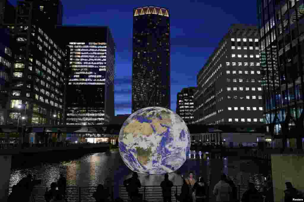 People look at Luke Jerram's "Floating Earth," an installation as part of the Canary Wharf Winter Lights festival in the financial district in London, Jan. 17, 2023.