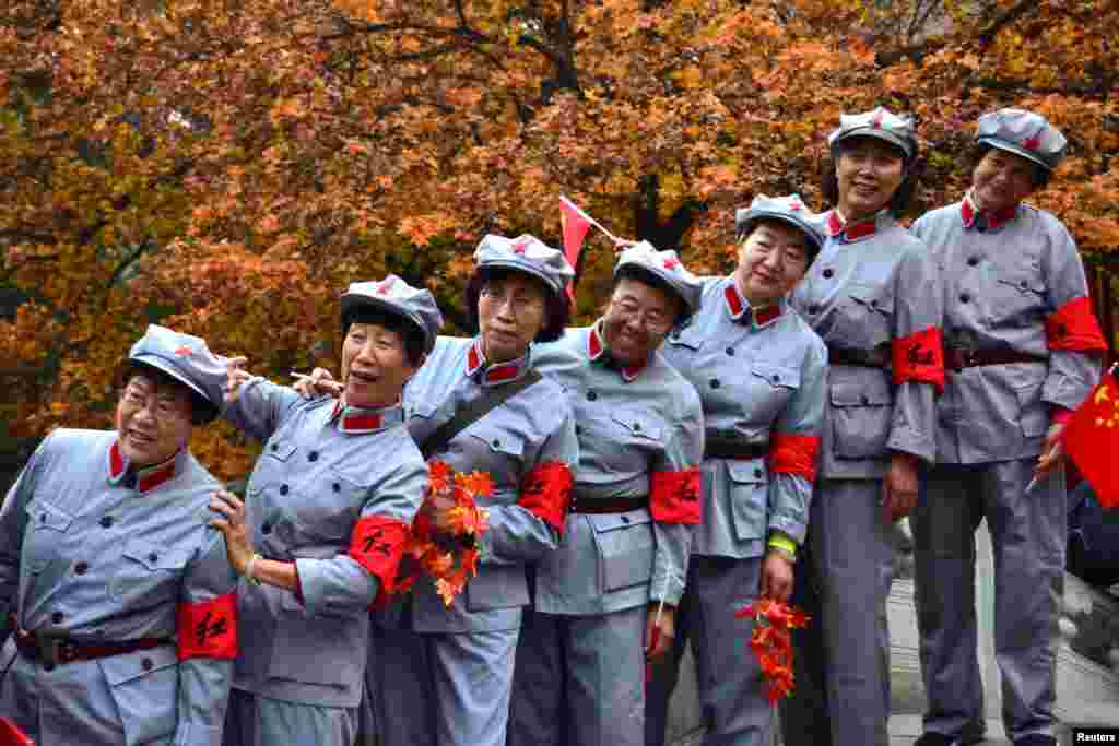 Women in replica red army uniforms have their picture taken as autumn leaves cover maple trees in Fragrant Hills Park in Beijing, China.