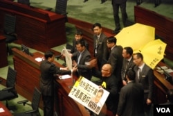 泛民主派立法会议员陈伟业(右)及陈志全在议会内，举起讽刺梁振英的标语，被保安人员抬离会场（美国之音汤惠芸拍摄）