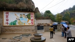 资料照片：在陕西省梁家河，中国最高领导人习近平青年时期生活过的窑洞外面，有一幅描绘青年习近平指引方向的壁画。（2016年10月22日）