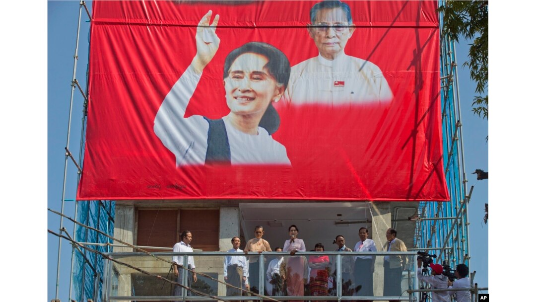 Leader of Myanmar's National League for Democracy party, Aung San Suu Kyi, center, delivers a speech from a balcony of the party headquarters in Yangon, Myanmar, Monday, Nov. 9, 2015.