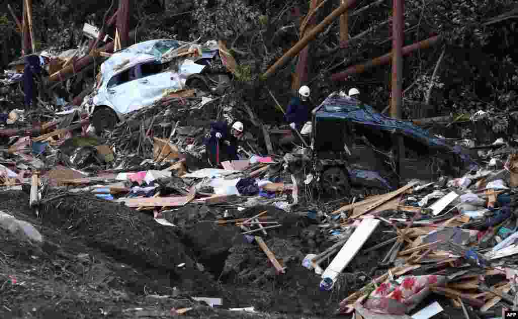 Fire brigade workers search survivors after a landslide buried houses caused by heavy rain of typhoon Wipha at Oshima island, 120km south of Tokyo, Japan.