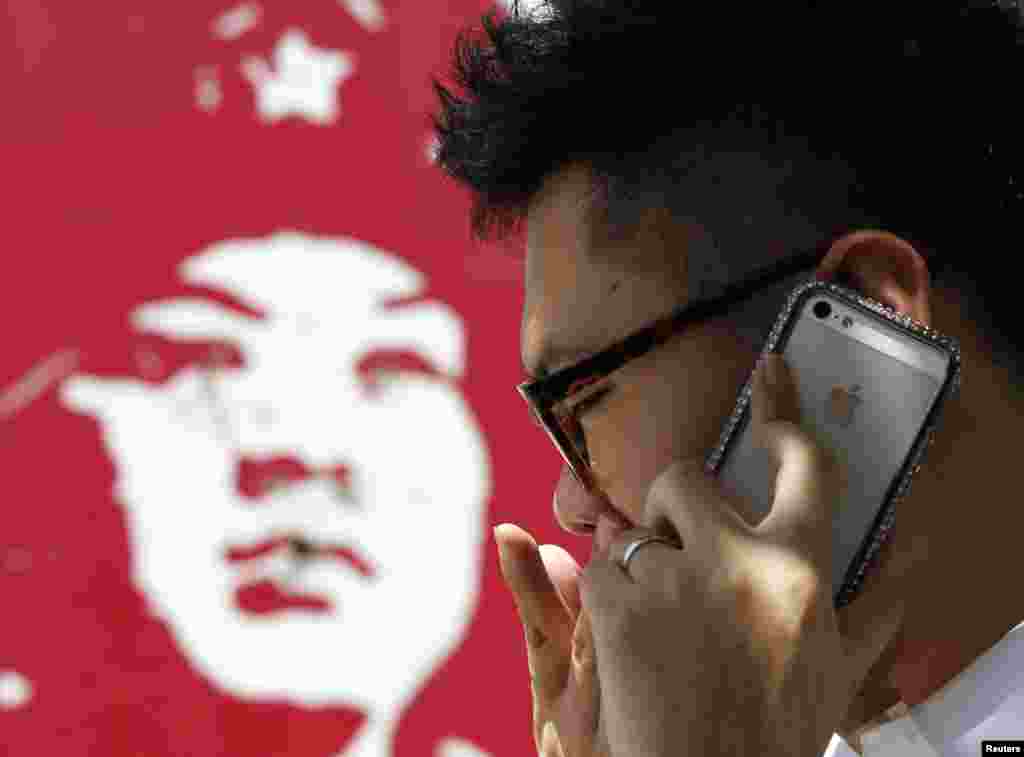 有中国人用苹果手机打电话，旁边是雷锋画像（2013年）。中国青年热衷于iPhone，而不是雷锋。