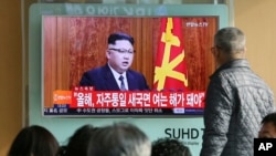 在首尔火车站，韩国人观看朝鲜领导人金正恩的电视新年讲话(2017年1月1日)