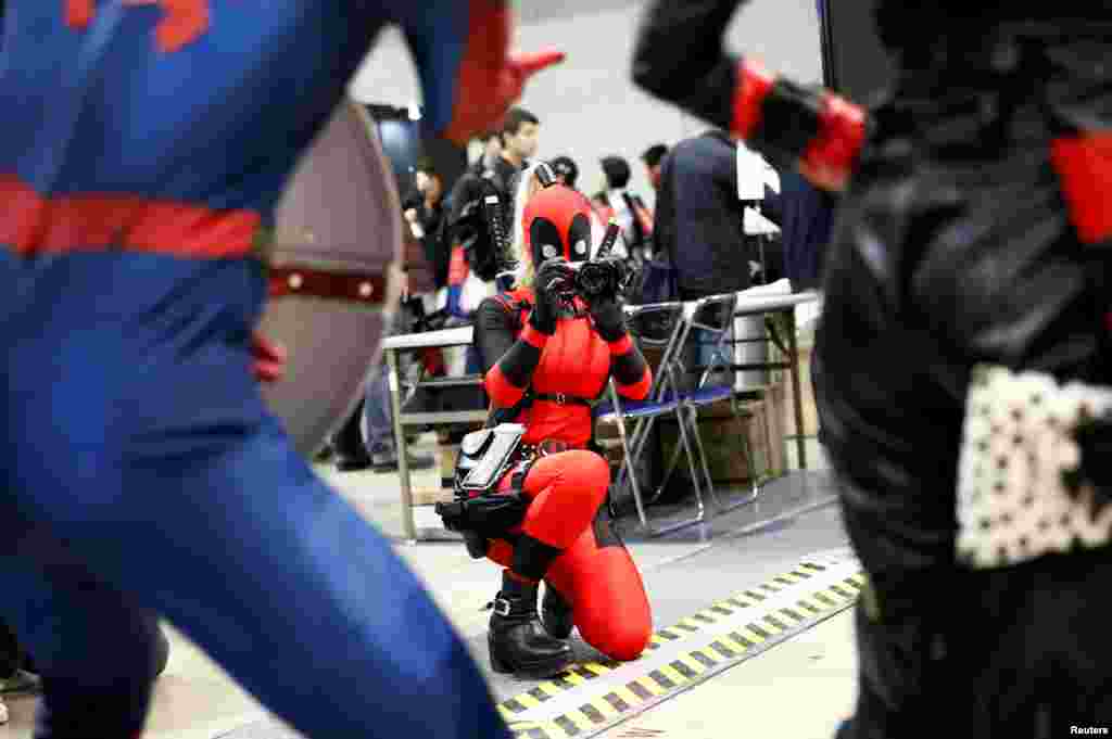 A woman in a Deadpool costume take a picture of other costume players at Tokyo Comic Con at Makuhari Messe in Chiba, Japan.