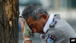 2023 年 7 月 3 日,在北京是炎热的一天。一位脖子上挂着电风扇的保安擦着汗。根据美国缅因大学气候再分析项目科学家的说法,周一和周二是非官方人类记录中最热的两天,整个地球都闷热难耐。 (美联社图片)