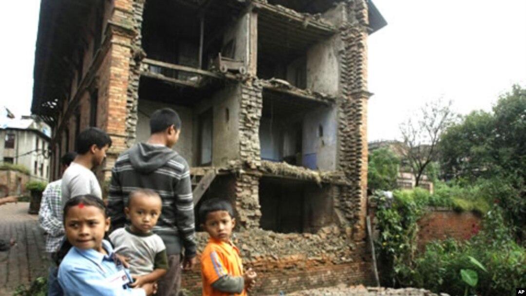 Nepalese children and other people stand near the debris of collapsed buildings damaged by an earthquake that shook northeastern India on Sunday night, in Katmandu, Nepal, September 19, 2011.