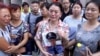 中国北部城市天津官员召开每日新闻发布会的宾馆外，一名女士拿着失踪的消防员儿子的照片。（2015年8月16日）