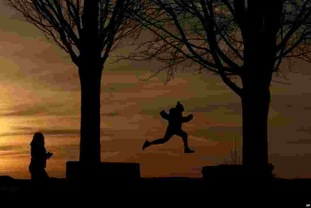 A child leaps between rock platforms as the sun sets behind Lake Erie at the Erie Basin Marina in Buffalo, New York, Dec. 2, 2017.