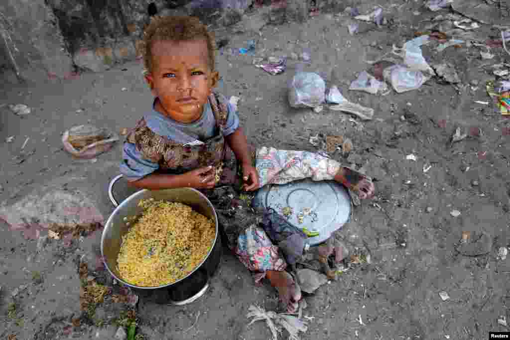 A girl displaced by the war in the northwestern areas of Yemen eats outside her family's makeshift hut on a street in the Red Sea port city of Hodeida.